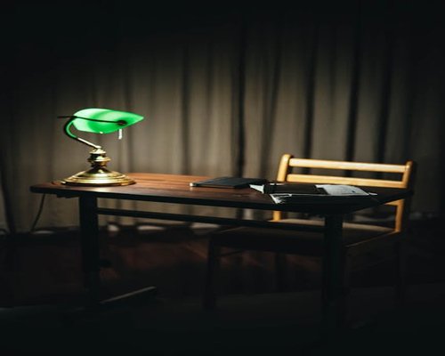 A warm desk lamp illuminating an open physical book in a dimly lit room